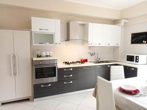 a kitchen with gray cabinets and white appliances at La Tortora in Cefalù