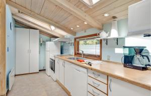 a kitchen with white appliances and a wooden ceiling at Le Coucou in Marielyst