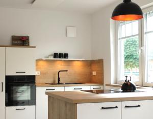 a kitchen with white cabinets and a black appliances at Pilsumer Küstenhuuske in Krummhörn