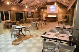 a dining room with tables and chairs and a screen at Hotel Rishiraj, Nagaon in Nowgong