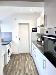 アシントンにあるSpacious 3 Bed Northumberland Long Stay Discountのキッチン(白いキャビネット、洗濯機、乾燥機付)