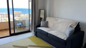 a blue couch in a living room with a balcony at Le plein soleil in Ajaccio +2 photos