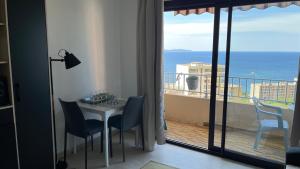 a room with a table and chairs and a balcony at Le plein soleil in Ajaccio