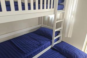 a bunk bed with two blue pillows and a ladder at Ground floor Studio in Golem Next to Hotel Flower self check in 100m to beach in Golem