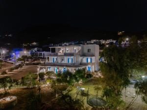 a large white building with blue doors at night at Dorkas Luxury Rooms&Apartments in Livadakia
