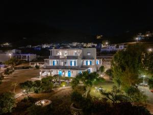 a large white building at night with a town in the background at Dorkas Luxury Rooms&Apartments in Livadakia