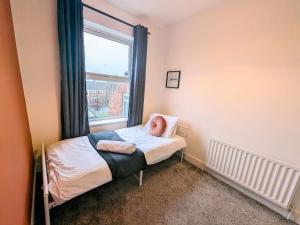 a small bedroom with a bed and a window at Lovely 3 Br Flat For Family, Friends And Workers in Gateshead