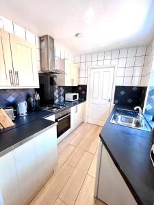 a kitchen with white cabinets and black counter tops at 3 Bdrm Home 10mins From The City in Heaton