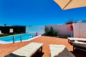 Un patio con piscina con sillas y una piscina. en El Salto 37 - Rinnovata 2023, Piscina Riscaldata, Sole tutto il giorno! Wi-Fi, Massima privacy, Ottima posizione, en Playa Blanca