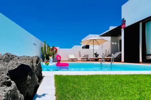 una piscina al lado de una casa con una sombrilla en El Salto 37 - Rinnovata 2023, Piscina Riscaldata, Sole tutto il giorno! Wi-Fi, Massima privacy, Ottima posizione, en Playa Blanca