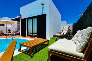 un patio trasero con una piscina con una silla y una mesa en El Salto 37 - Rinnovata 2023, Piscina Riscaldata, Sole tutto il giorno! Wi-Fi, Massima privacy, Ottima posizione, en Playa Blanca