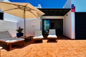 un patio con dos sillas y una sombrilla en El Salto 37 - Rinnovata 2023, Piscina Riscaldata, Sole tutto il giorno! Wi-Fi, Massima privacy, Ottima posizione, en Playa Blanca 41 fotos más
