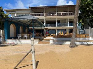 a building with a porch with chairs and a table at Sea Sands Beach Hostel in Negombo