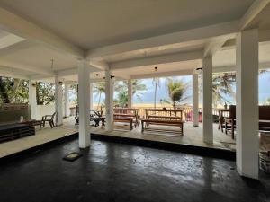 a porch with benches and tables on the beach at Sea Sands Beach Hostel in Negombo