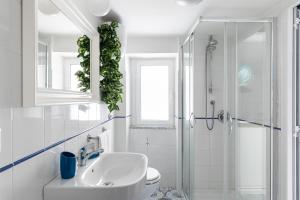 een witte badkamer met een wastafel en een douche bij La cianciola in Gaeta