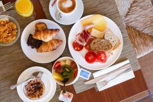 a table with plates of breakfast foods and a cup of coffee at Hotel Blaumar Cadaqués by Fimedhotels in Cadaqués