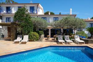 a villa with a swimming pool and chairs and a building at Hotel Blaumar Cadaqués by Fimedhotels in Cadaqués