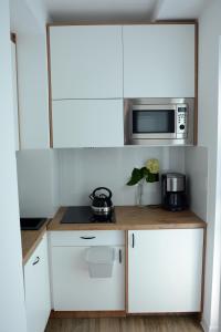 a kitchen with white cabinets and a microwave at Apartament Młyńska 26 in Augustów +7 photos