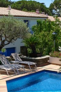 a swimming pool with two chairs and a house at Hotel Blaumar Cadaqués by Fimedhotels in Cadaqués
