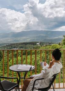 a woman sitting in a chair on a balcony with a table at Złoty Horyzont Resort Szklarska Poręba in Szklarska Poręba