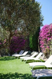 a row of white lounge chairs in a park with pink flowers at Hotel Blaumar Cadaqués by Fimedhotels in Cadaqués