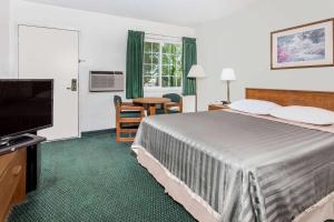 a hotel room with a bed and a flat screen tv at Travelodge by Wyndham Grants Pass in Grants Pass +19 photos