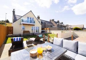 a patio with a table and chairs and a house at Aurora House Hot Tub & Sea View in Buckie