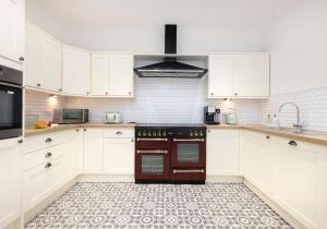 a kitchen with white cabinets and a stove top oven at Aurora House Hot Tub & Sea View in Buckie