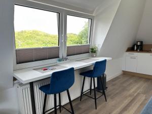 eine Küche mit zwei blauen Stühlen an einer Theke mit Fenster in der Unterkunft MainQuartier in Norderney