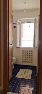 a bathroom with a window and a blue tile floor at casa bisnonna pina in Ponza