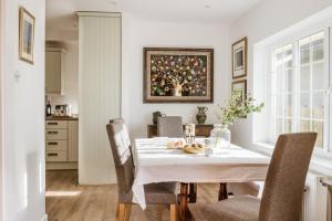 une salle à manger avec une table et des chaises blanches dans l'établissement Beachside, Luxury Cottage, Devon, à Thurlestone