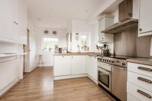 une cuisine avec des armoires blanches et des appareils en acier inoxydable dans l'établissement Beachside, Luxury Cottage, Devon, à Thurlestone