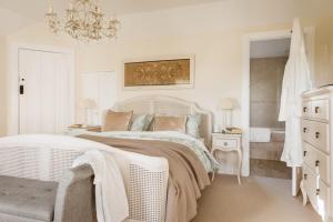 - une chambre blanche avec un lit et un lustre dans l'établissement Beachside, Luxury Cottage, Devon, à Thurlestone