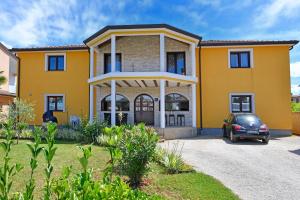 ein gelbes Haus mit einem Auto vor dem Haus in der Unterkunft Apartments Dulabic in Poreč