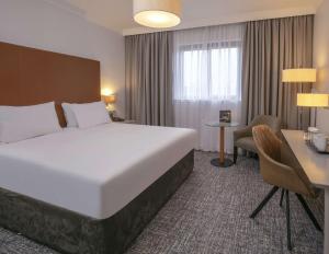 a hotel room with a large bed and a desk at Glasgow Westerwood Hotel, Spa & Golf Resort in Cumbernauld