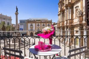 Una mesa con un jarrón de flores en un balcón. en Vista San Domenico, en Palermo