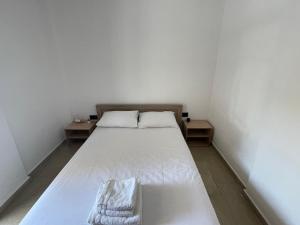 a white bed in a small room with two tables at Ntina's Room in Nea Potidaea