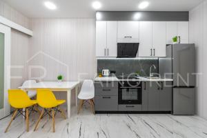 a kitchen with yellow chairs and a table and a refrigerator at Панорамний вид моря дві спальнi та зала 0522 in Odesa