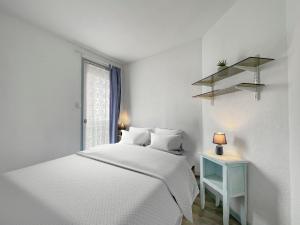 a white bedroom with a white bed and a blue table at Évasion Balnéaire au Cap d'Agde in Cap d'Agde
