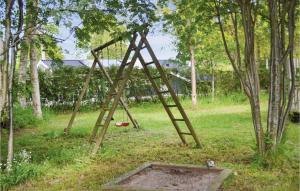 a wooden swing set in a field with trees at Holiday Home Villesensvej Ii in Fjellerup
