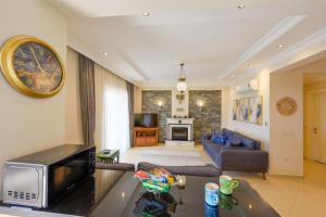 a living room with a couch and a tv at Villa Arokarya in Fethiye