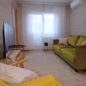 a living room with a green couch and a television at Yasmin Apartment in Pärnu +8 photos