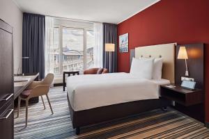 Una habitación de hotel con una cama grande y un escritorio. en Dorint Hotel Esplanade Jena, en Jena