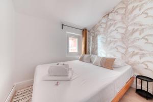 Una cama blanca en una habitación con una pared. en GuestReady - Aptos modernos em Lyon, en Fourvière