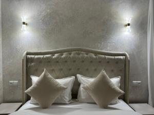 ein Bett mit weißen Kissen und zwei Lampen darüber in der Unterkunft Royal Renaissance hotel in Yerevan