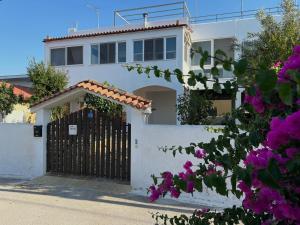 a white house with a gate and purple flowers at Naja's Studio in Souvala