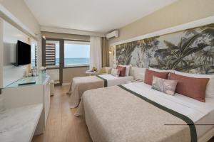 a hotel room with two beds and a television at Adin Resort Hotel - Halal All Inclusive in Avsallar