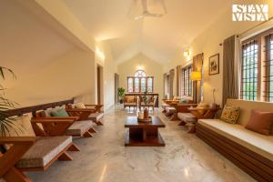 a living room with couches and tables and windows at StayVista at Spice Notes - Breakfast Included in Munnar