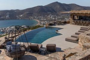 a swimming pool with chairs and a view of the water at Alma Sunset Suites in Ios Chora