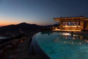 a large swimming pool with a gazebo at night at Alma Sunset Suites in Ios Chora